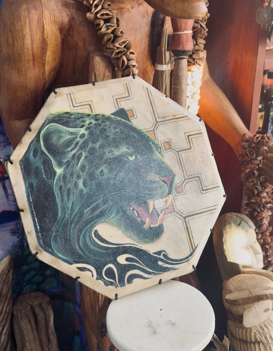 Shamanic drum painted with a jaguar, displayed among wooden carvings